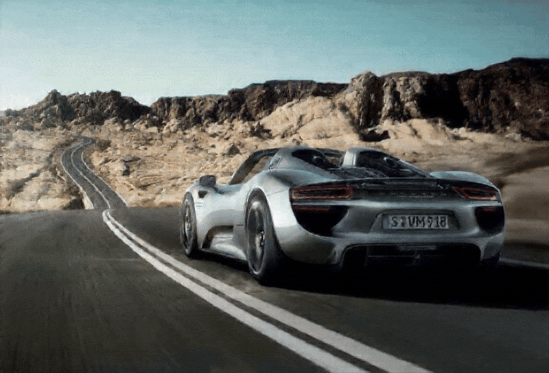 Una Porsche 918 Spyder corre ad alta velocità su un'autostrada deserta all'alba. La luce del sole riflette sulla carrozzeria mentre l'auto sfreccia fluida tra le curve. La scena è cinematografica, con inquadrature dinamiche e dettagli su luci, movimento e design. L'atmosfera è potente e silenziosa.